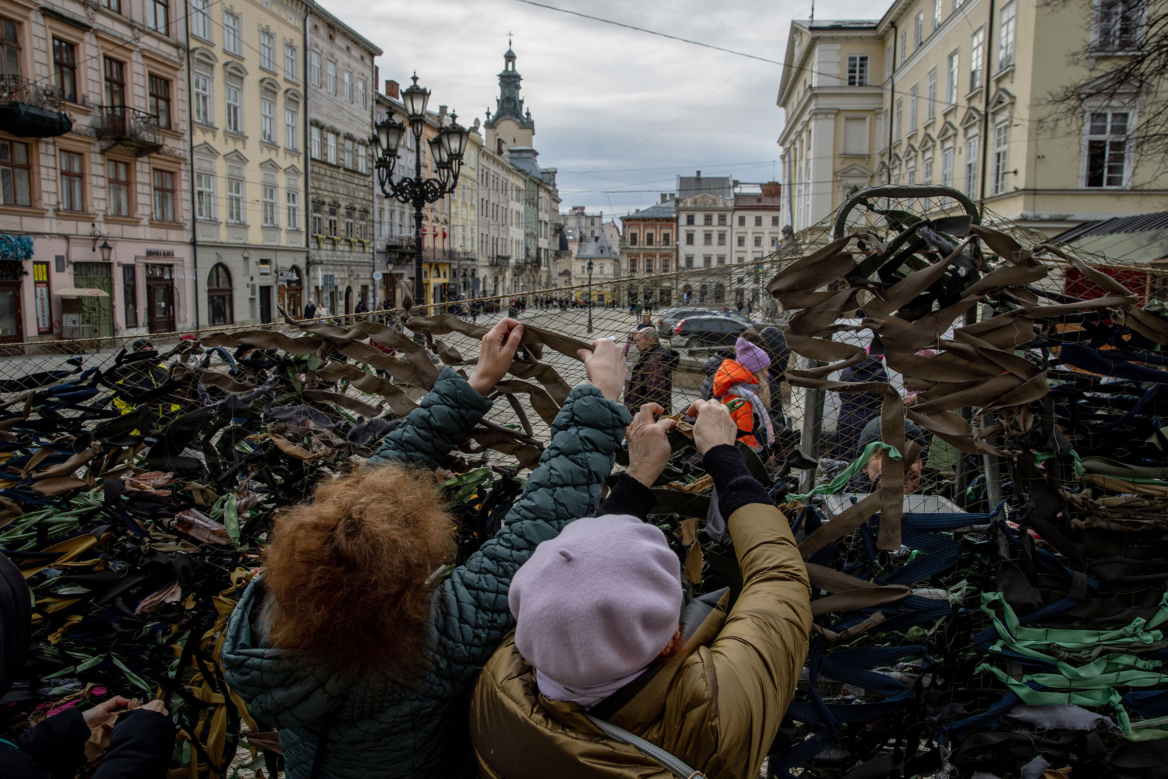 Volunteers tie pieces of fabric while making camouflage nets outside the Ivanychuk Library in Lviv on March 1. (Ethan Swope—Bloomberg/Getty Images)