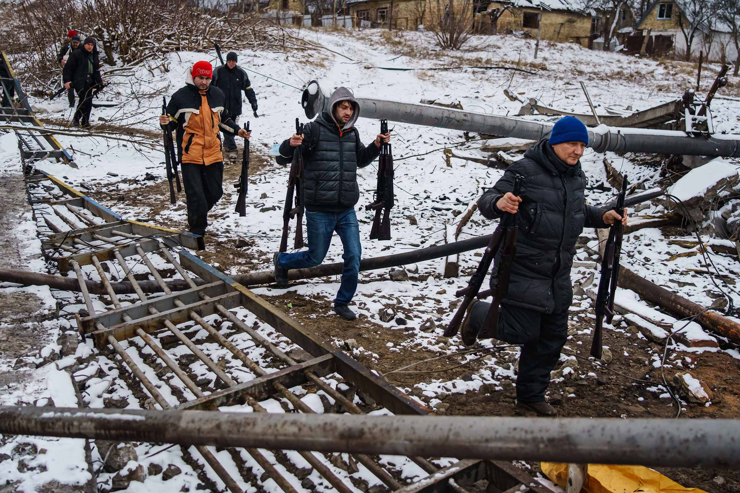 Volunteer fighters transport rifles across a river under a destroyed bridge to reinforce Ukrainian troops in Irpin on March 1. (Marcus Yam—Los Angeles Times/Getty Images)
