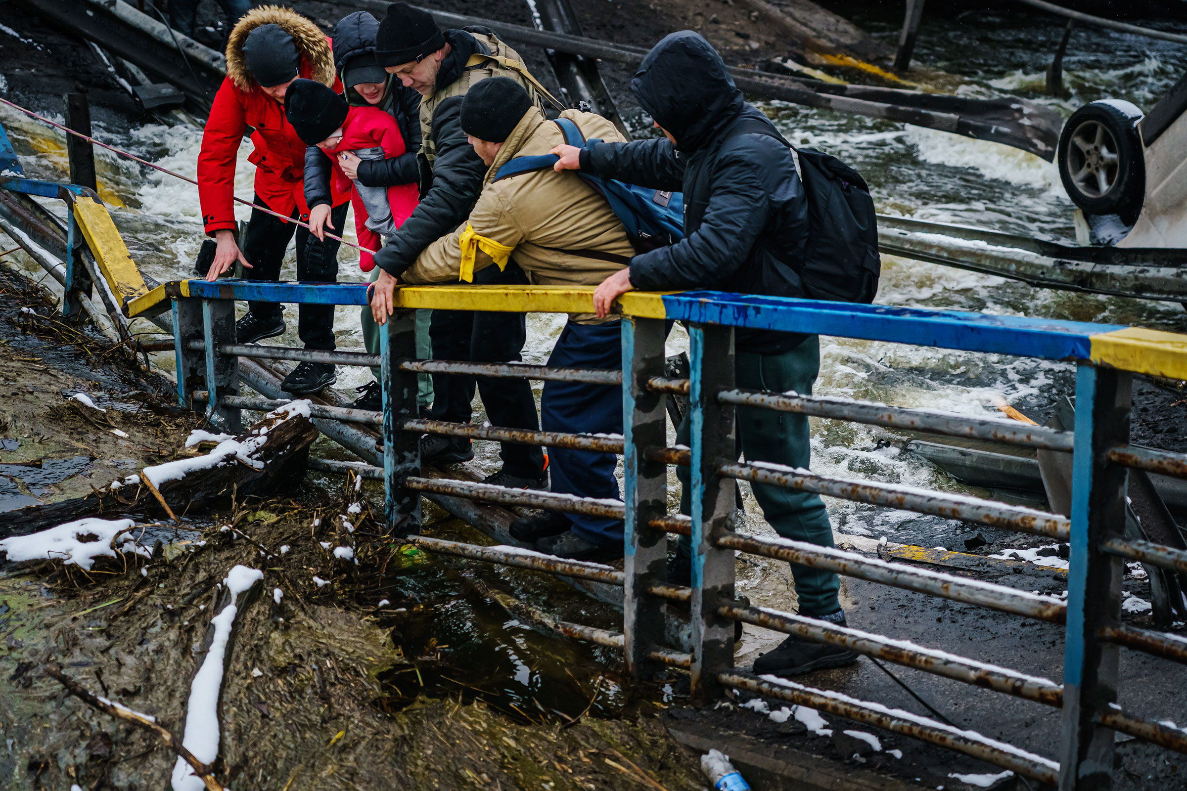 Soldiers help a couple and their infant child cross a broken bridge over the Irpin river that was destroyed to stop the advancing of Russian tanks as they flee their city of Irpin, on March 1.