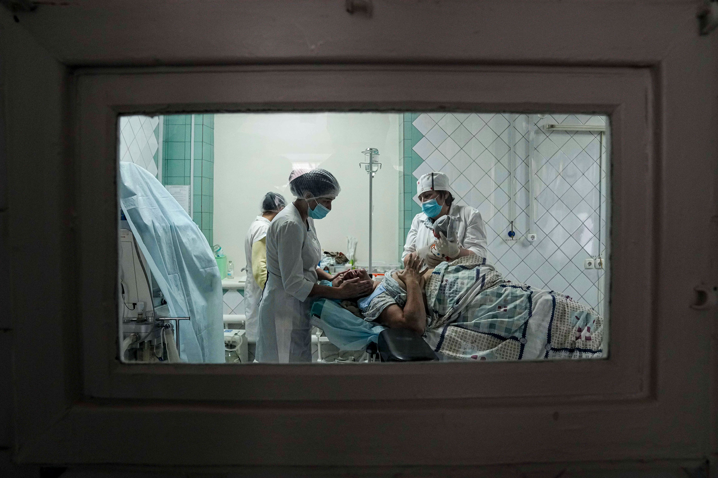 Medical workers show a newborn baby to a woman who gave birth in a maternity hospital converted into a medical ward in Mariupol on March 1. (Evgeniy Maloletka—AP)