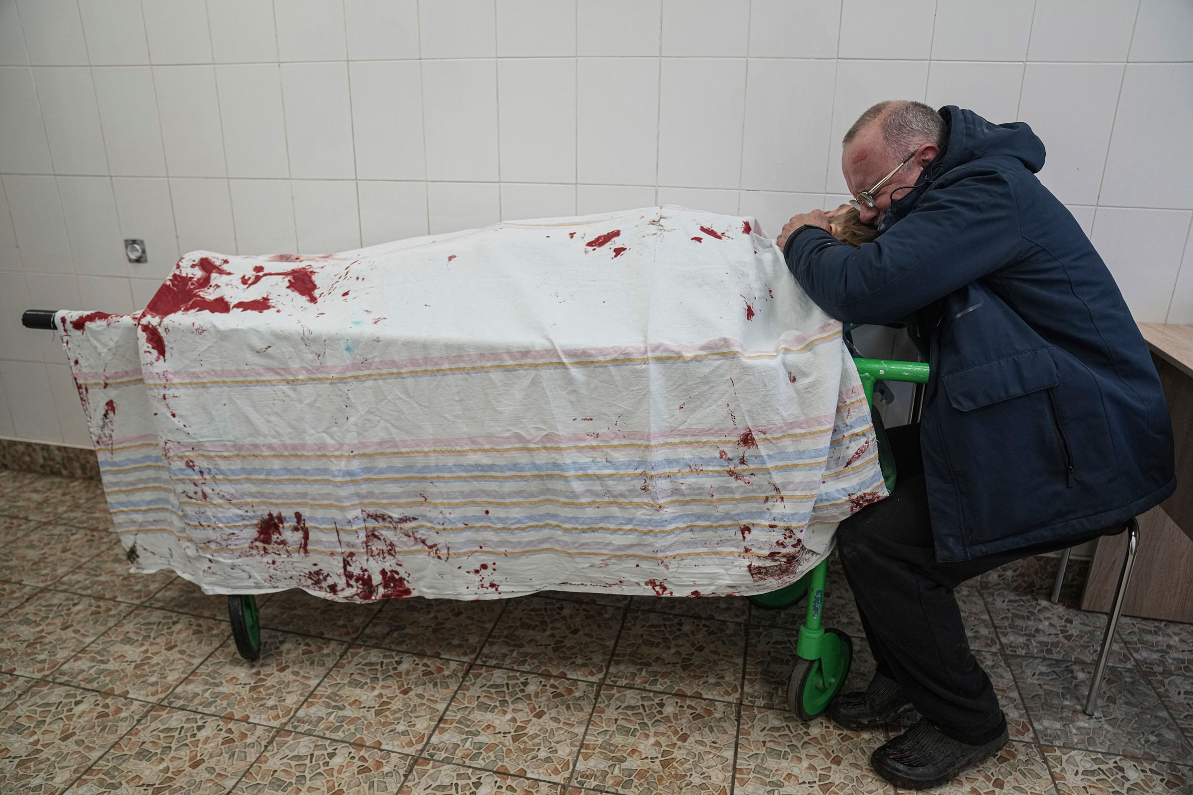 Serhii, father of teenager Iliya, cries on his son's lifeless body lying on a stretcher at a maternity hospital converted into a medical ward in Mariupol on March 2. Iliya was fatally wounded Wednesday while playing soccer in Mariupol when shelling started amid the Russian invasion of Ukraine. The explosive hit the soccer field near a school in the Azov Sea city. (Evgeniy Maloletka—AP)
