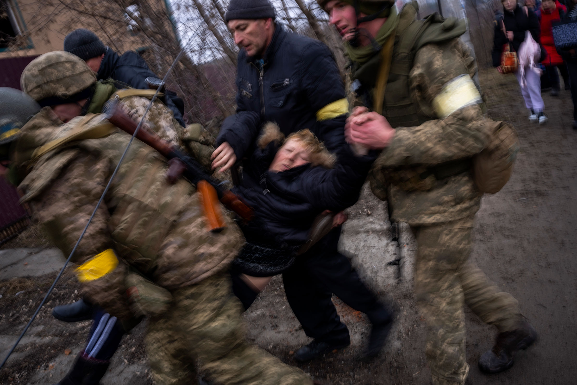 A sick woman in a semi-conscious state is carried by Ukrainian soldiers as they cross the Irpin river while fleeing the city in the outskirts of Kyiv on March 5.