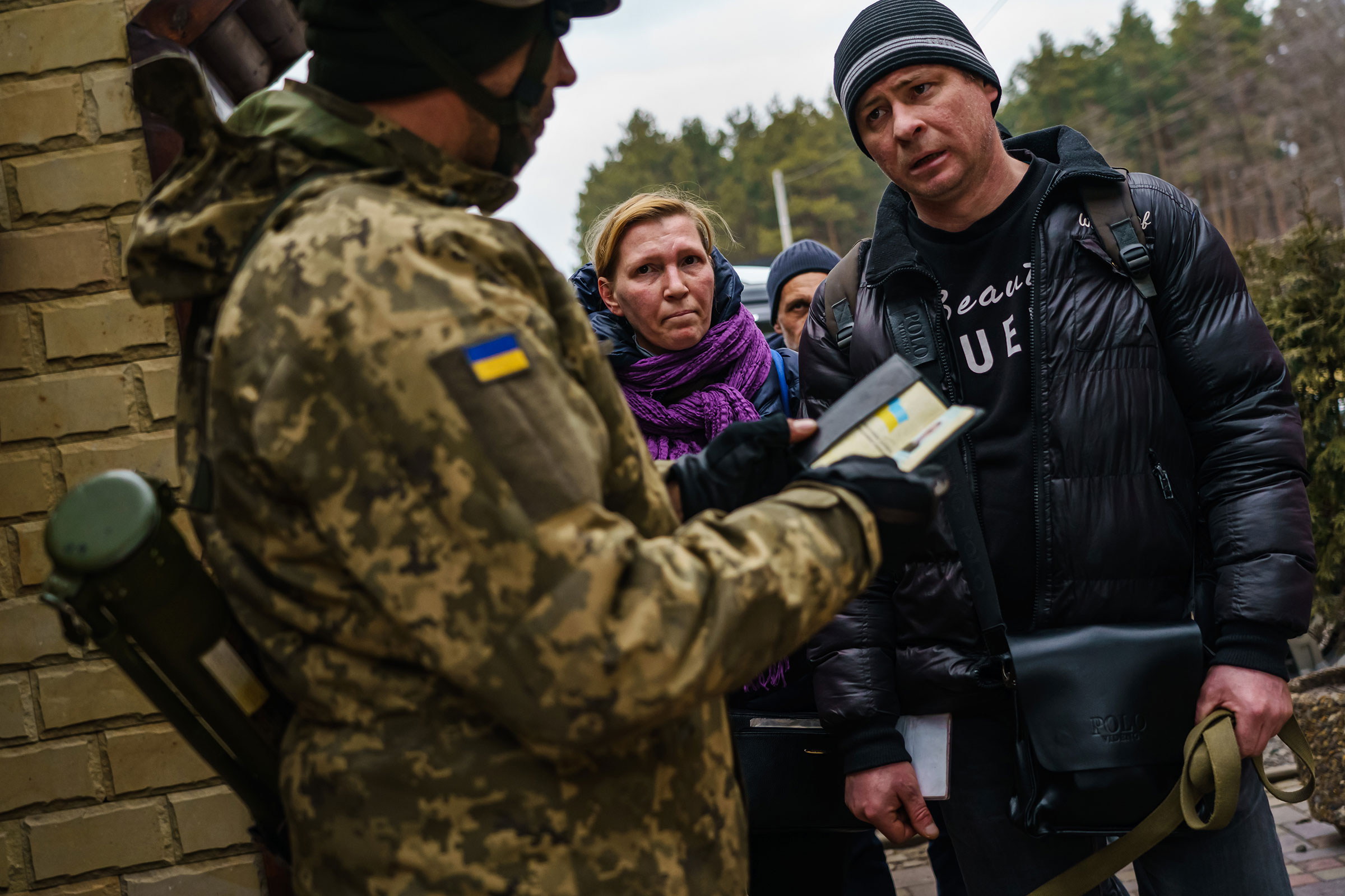 Civilians get their documents checked by soldiers as they evacuate Irpin on March 6.