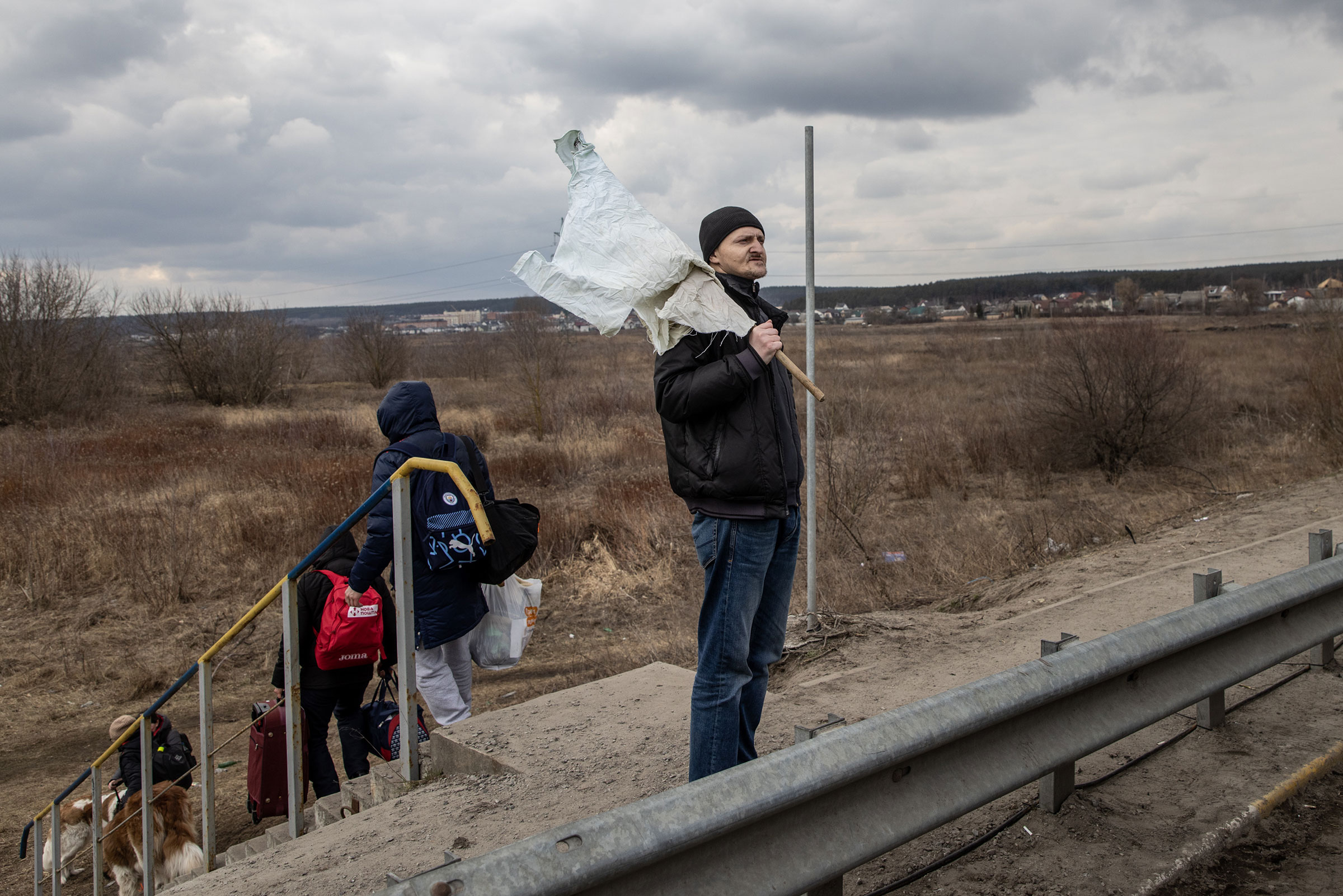 A resident holds a white flag as he flees heavy fighting via a destroyed bridge as Russian forces entered the city of Irpin on March 7. (Chris McGrath—Getty Images)