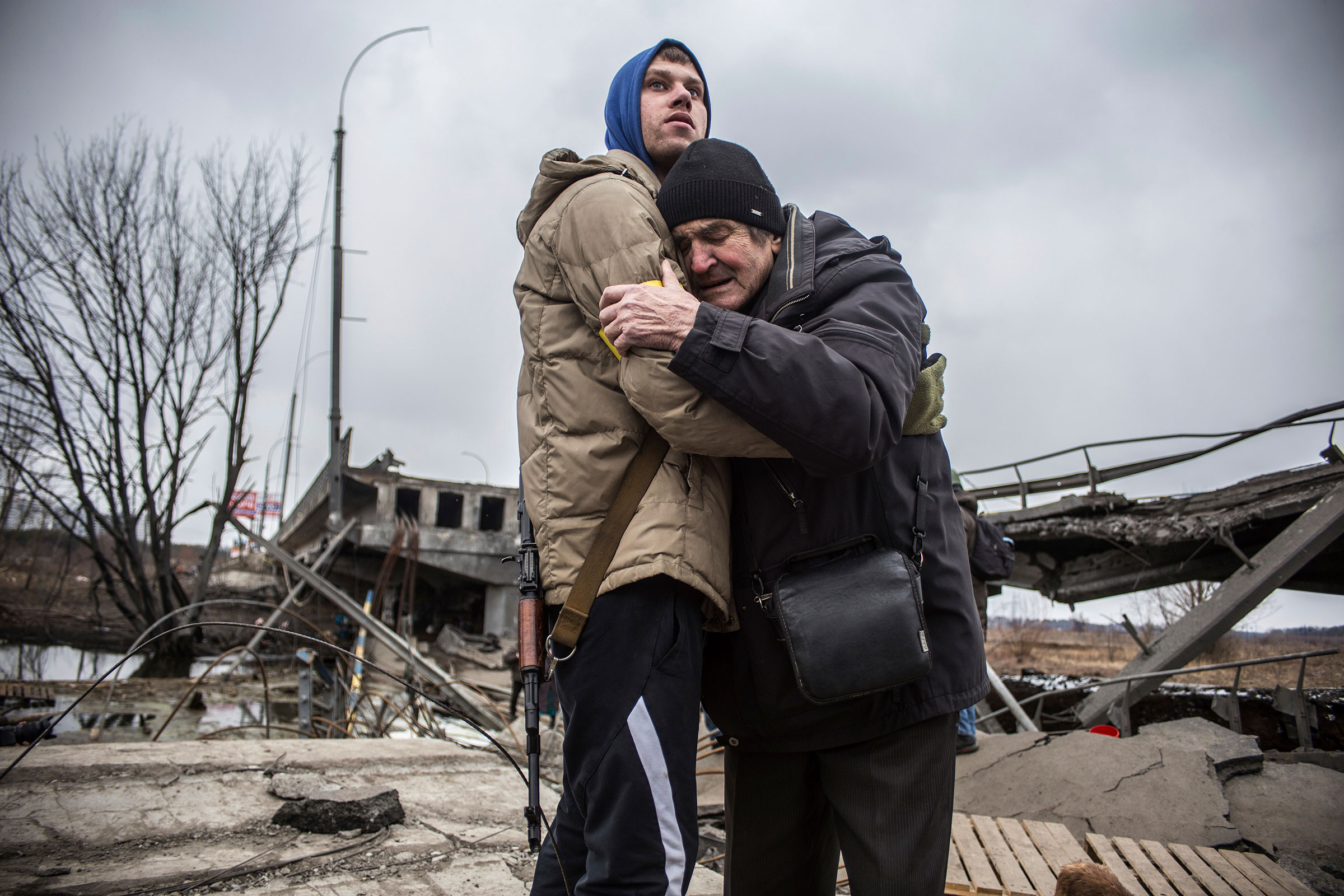 A Ukrainian Territorial Defense Forces member hugs a resident who leaves his home town following Russian artillery shelling in Irpin on March 9.