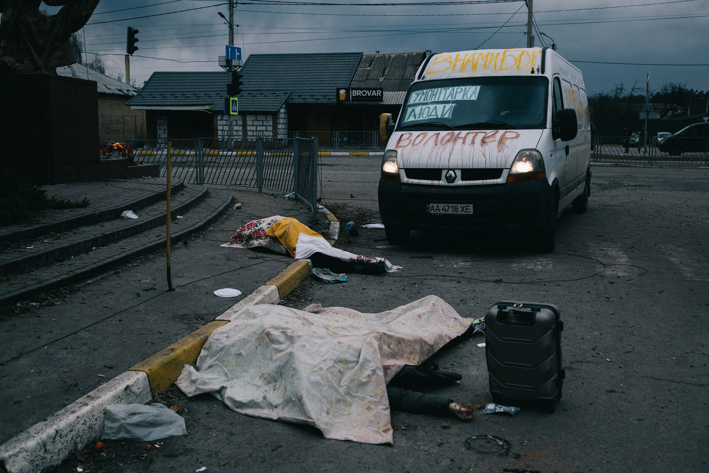 The bodies of civilians killed by a Russian mortar attack while fleeing Irpin, near Kyiv, on March 6. A volunteer humanitarian aid van parked beside the scene had the words "God is with us" painted yellow on top (Maxim Dondyuk)