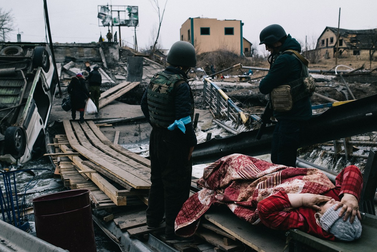 The military and volunteers help elderly people cross the blown-up bridge across the Irin River, through which residents are being evacuated to the city of Kyiv. Irpin city, Kyiv region, 12.03.2022