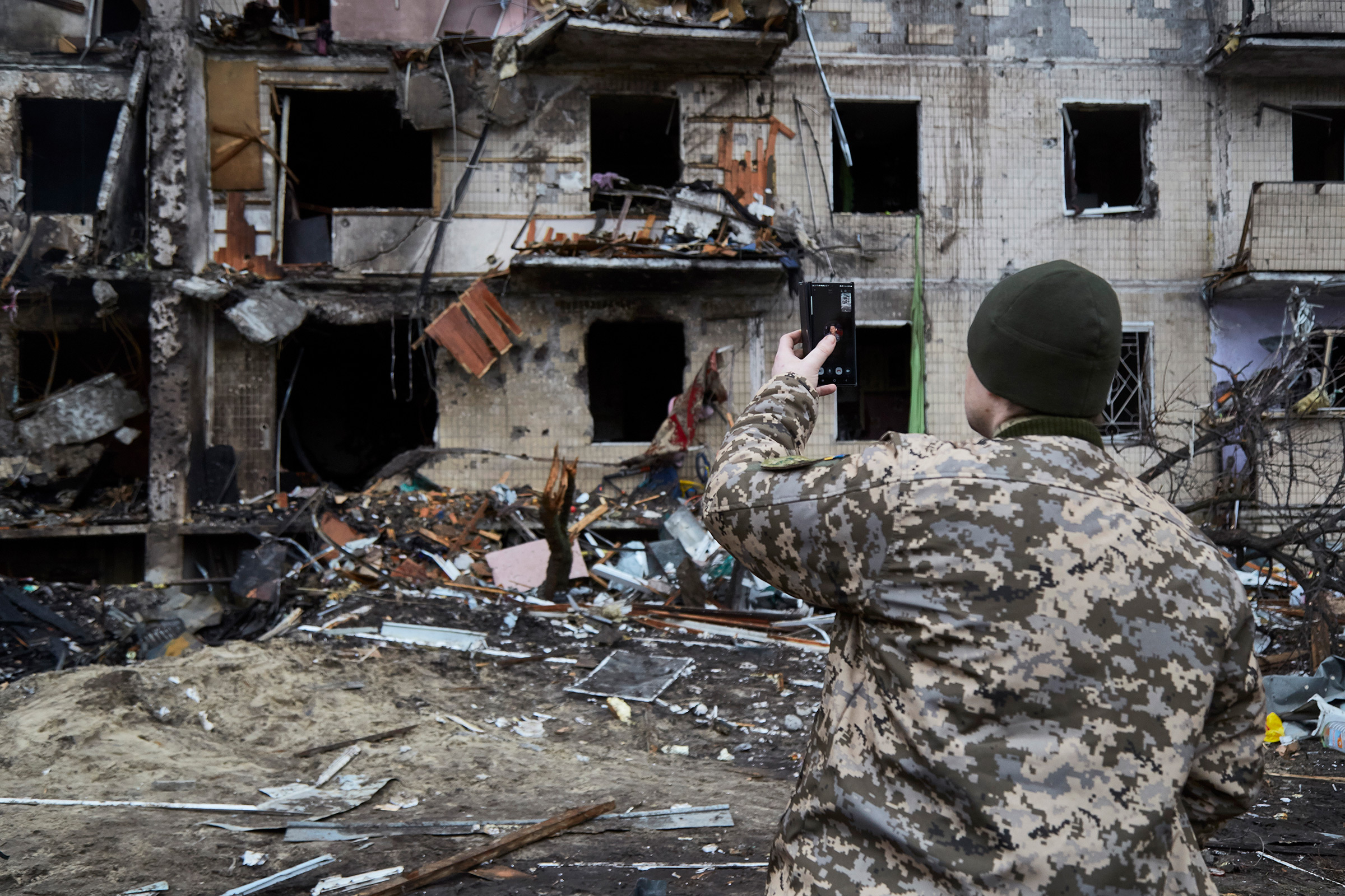 A Ukrainian soldier speaks on his smartphone outside a residential building damaged by a missile in Kyiv, Ukraine, on Feb. 25, 2022.
