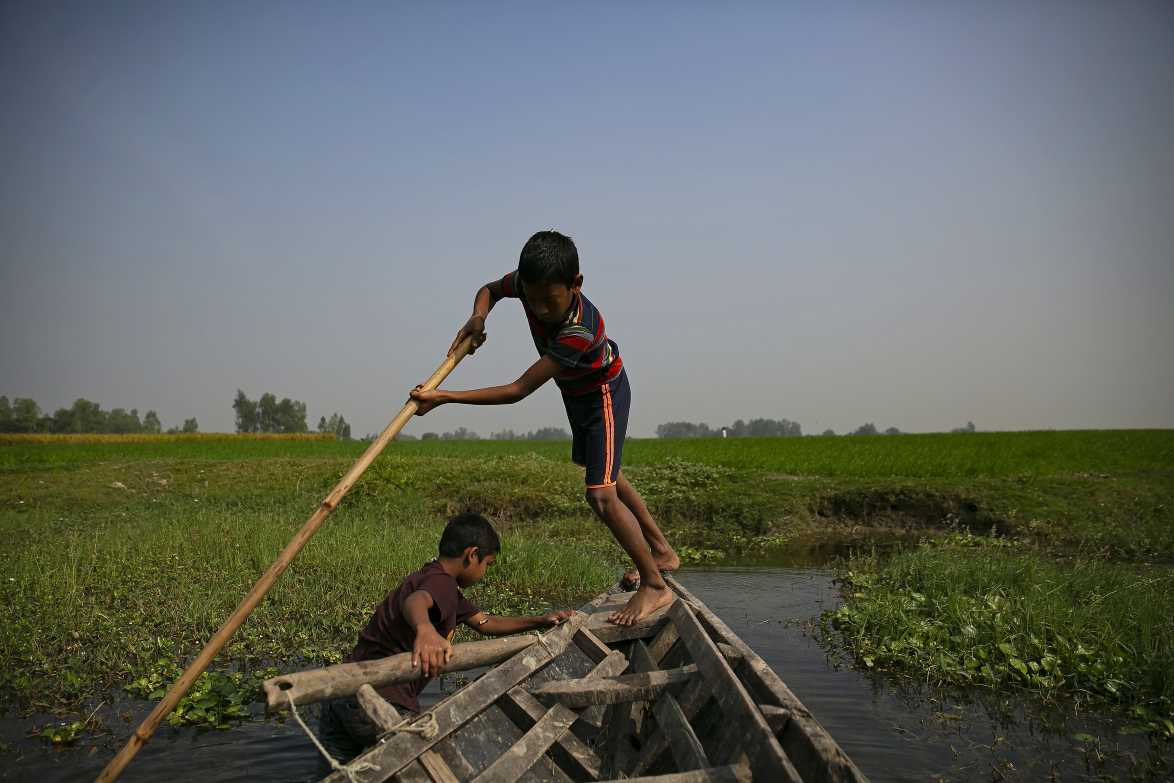 Alomgir, 11, steers a boat toward a field where he can collect grass for his family’s animals in Kushtia district on Dec. 14, 2021. (Allison Joyce)