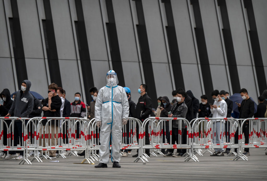 A health worker wears a protective suit as he directs people where to line up for nucleic acid tests to detect COVID-19 at a makeshift testing site in the Central Business District in Chaoyang on April 27, 2022 in Beijing, China. (Kevin Frayer/Getty Images)