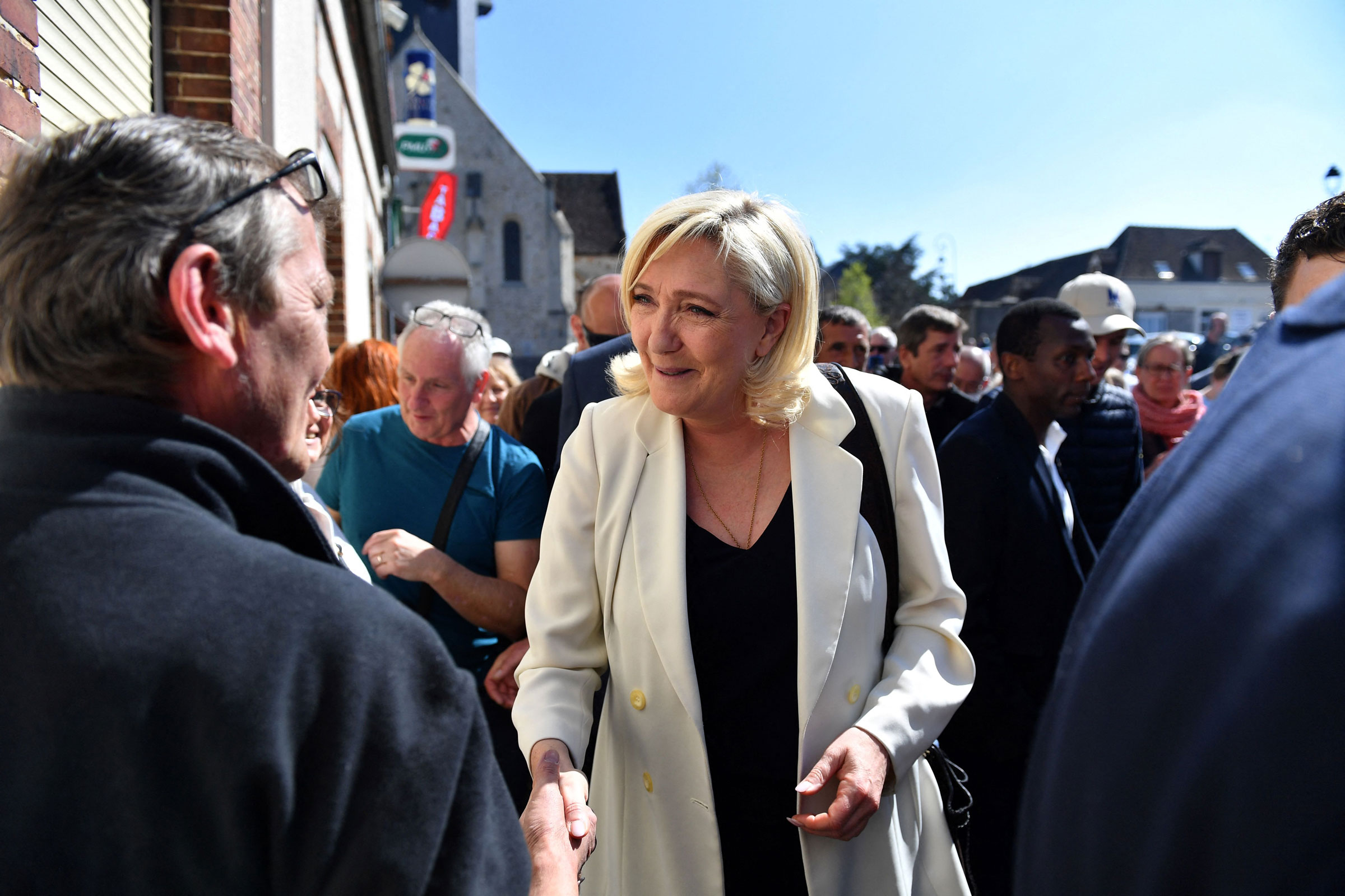 Marine Le Pen shakes hands with a member of the public during a campaign visit