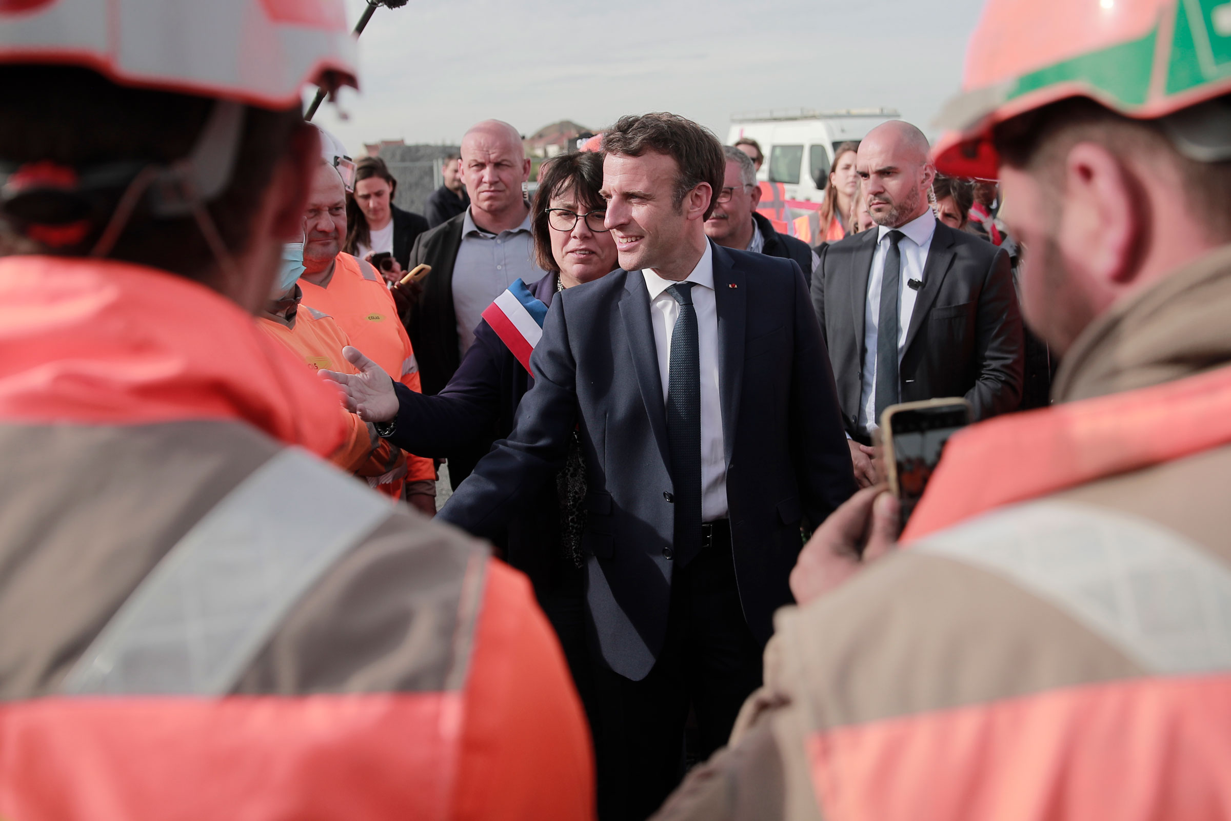 Current French President Emmanuel Macron and local mayor Anne-Lise Dufour-Tonini meet workers as he visits a building site in Denain, northern France, on April 11. (Lewis Joly—Pool/AP)