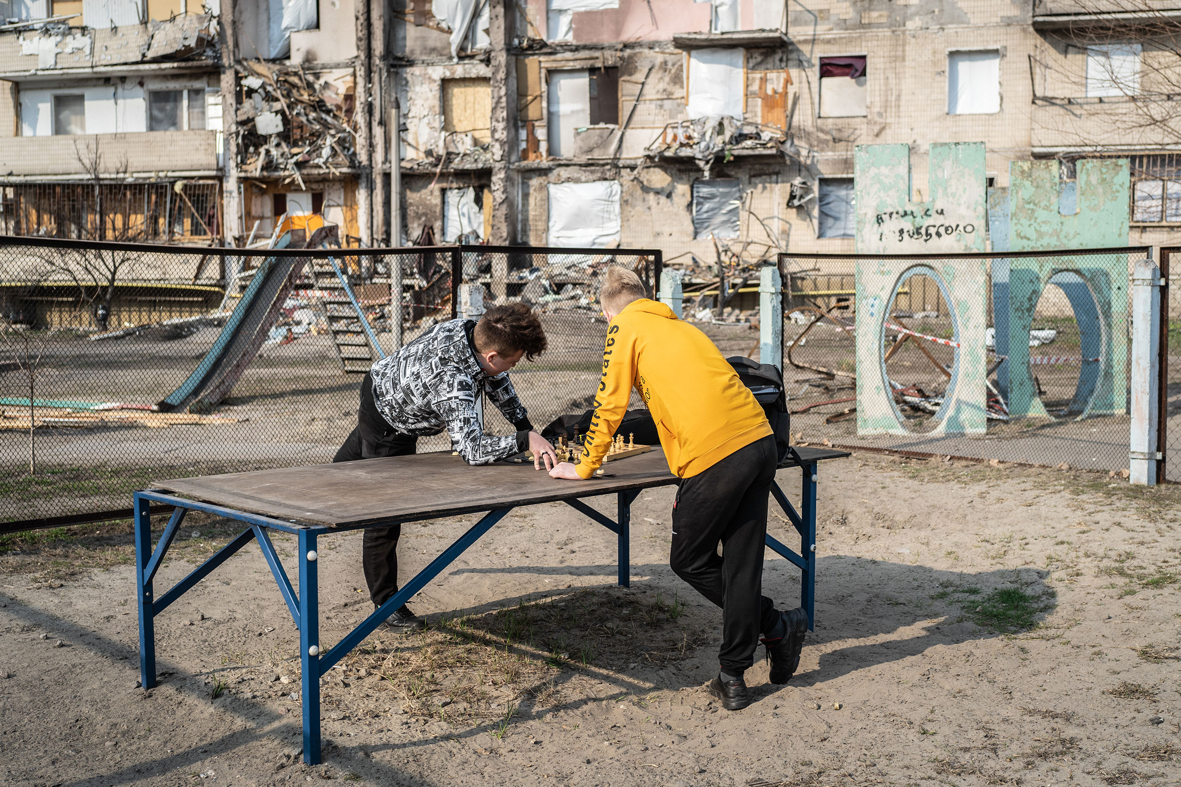 Sasha and Anton, both 15, play chess near a ruined building in Kyiv on March 24. (Serhii Korovainyi)