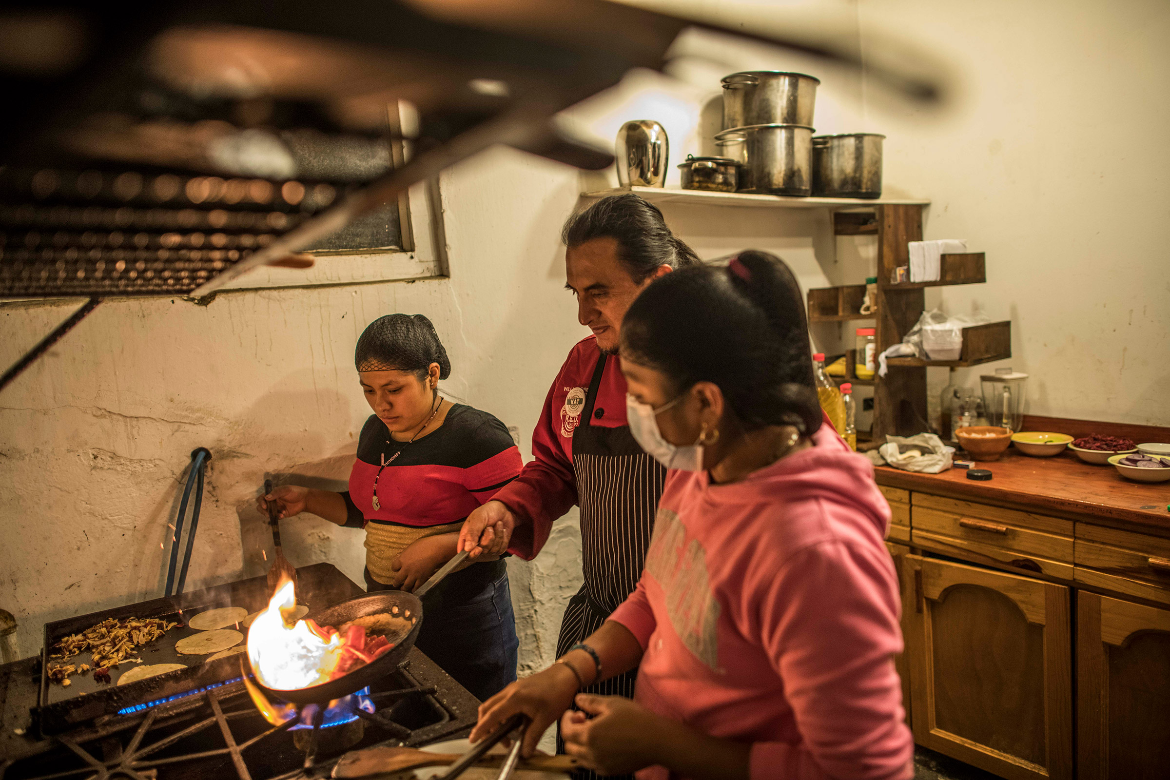 Willy Barreno (red shirt) leading the kitchen of La Red.Quetzaltenango, Quetzaltenango, Guatemala. April 8, 2022.Willy Barreno, 49, after spent 14 years in the US, between 1996 and 2010, as a regular migrant, decided to come back in his born land, Guatemala. After got experience as cook in New Mexico and back in Quetzaltenango, he opened his own place, La Red, serving Mexican dishes infused with Guatemalan flavors and ingredients. He dreamed of usingselling produce from local farmers and employing other returned migrants. But today La Red is hanging by a thread. Barrenos says he relies on donations from friends and family to keep it open week to week.