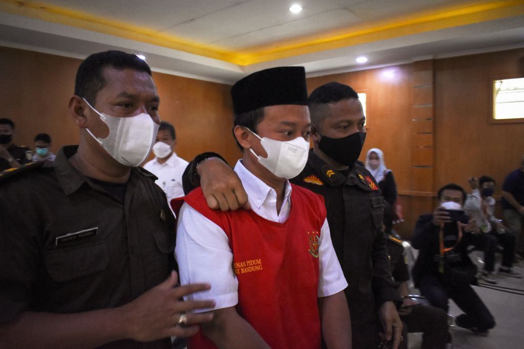 Indonesian teacher Herry Wirawan (C) is escorted prior to his trial at a court in Bandung, West Java on Feb. 15, 2022. In April, he was sentenced to death for the rape of at least 13 students, all minors. (Timur Matahari–AFP/Getty Images)