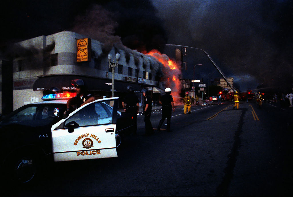 LOS ANGELES - APRIL 30:  Rodney King Riot. A view of intersection of Pico Boulevard and Hayworth Avenue during the Rodney King Riots showing Beverly Hills Police Department officers on periphery of burning businesses, Los Angeles Fire Department firemen fighting fires beyond them, and the sky black with smoke in daylight on April 30, 1992 in Los Angeles, California.  (Photo by Lindsay Brice/Getty Images) (Lindsay Brice—Getty Images)