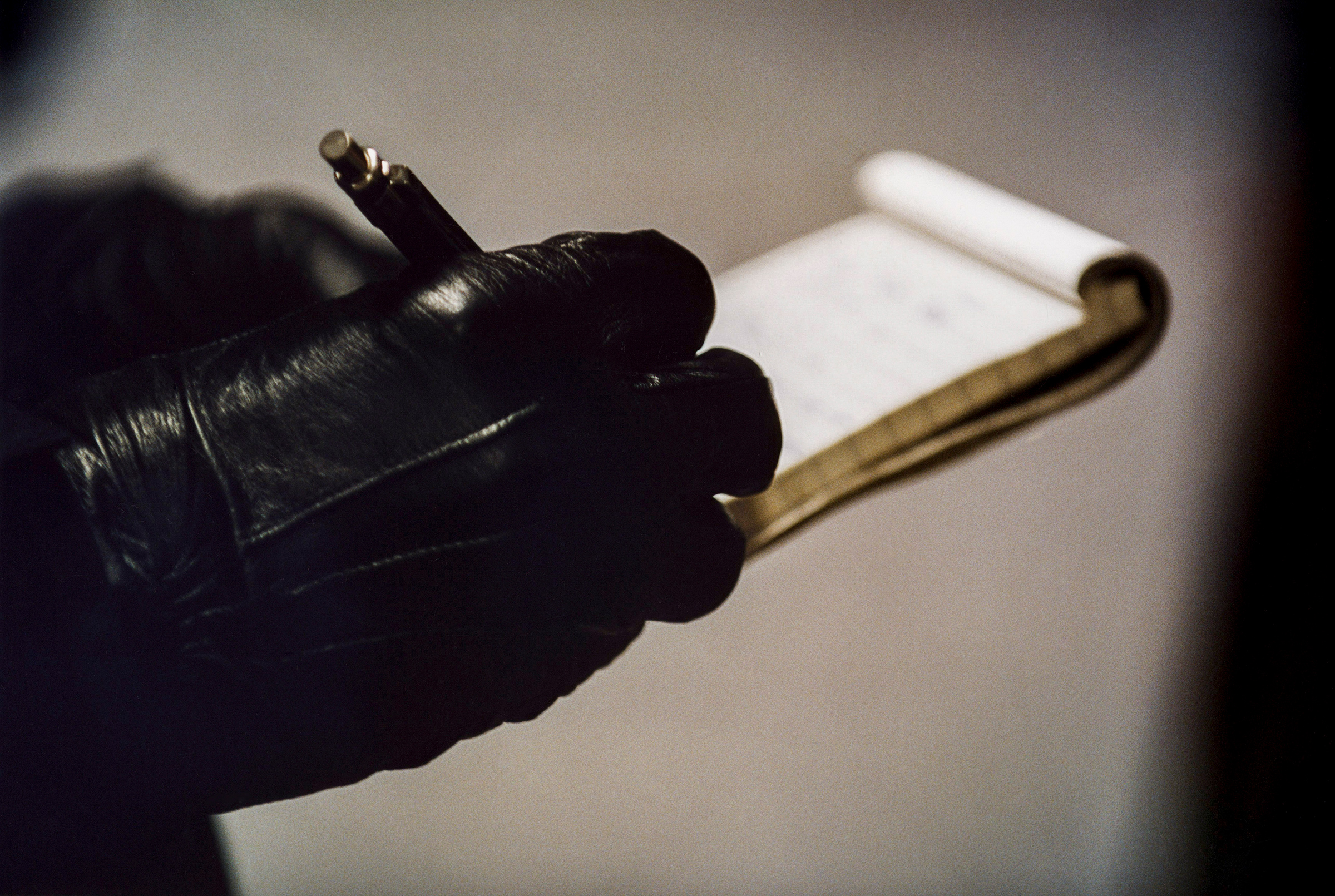 A police officer's hand in gloves write on a notepad.