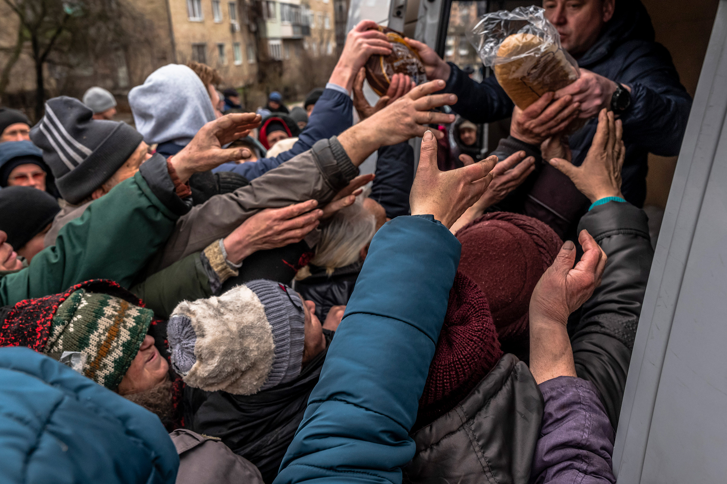 Residents reach for food being distributed by soldiers from the Azov battalion, a Ukrainian paramilitary, in Bucha, a recently-liberated town northwest of Kyiv, Ukraine, on April 2, 2022.