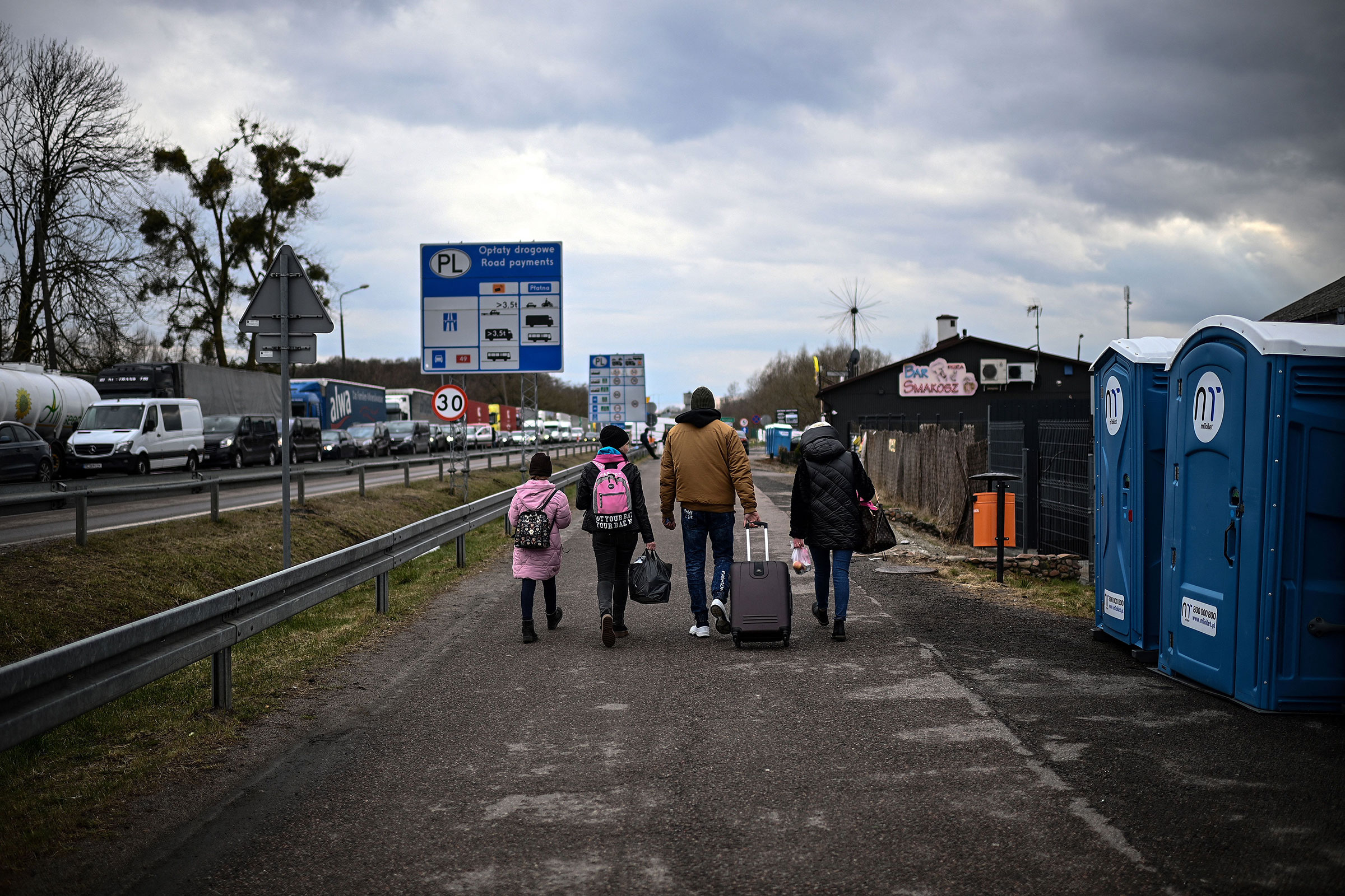 Ukrainian refugees Julia and Miroslava walk away with relatives (R) who picked them up after they crossed the Ukrainian-Polish border on their way out of Ukraine at the Dorohusk border crossing, eastern Poland on April 6, 2022. (Christophe Archambault—AFP/Getty Images)
