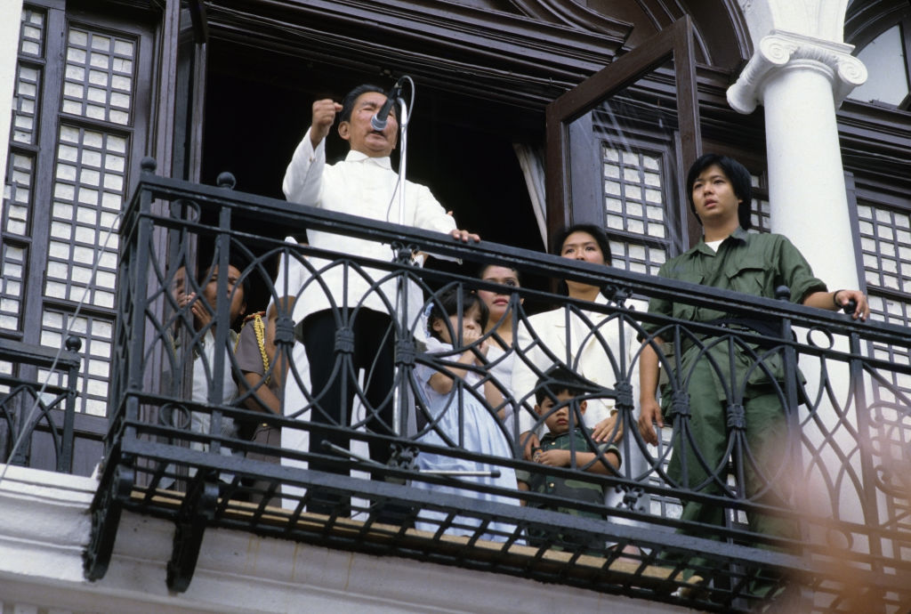 Philippine President Ferdinand Marcos delivering his last speech to supporters from the balcony of Malacanang Palace in Manila in February 1986 before the family was forced to flee aboard American helicopters following a people's movement. His son and future leader Bongbong is standing far right. (Alex Bowie–Getty Images)
