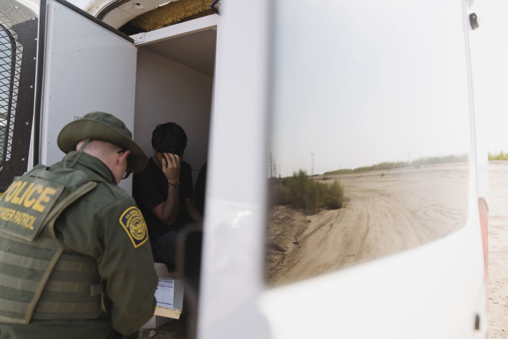 A U.S. Border Patrol agent apprehends a migrant near the U.S.-Mexico border fence in Calexico, California on Tuesday, Sept. 14, 2021. (Eric Thayer/Bloomberg via Getty Images)