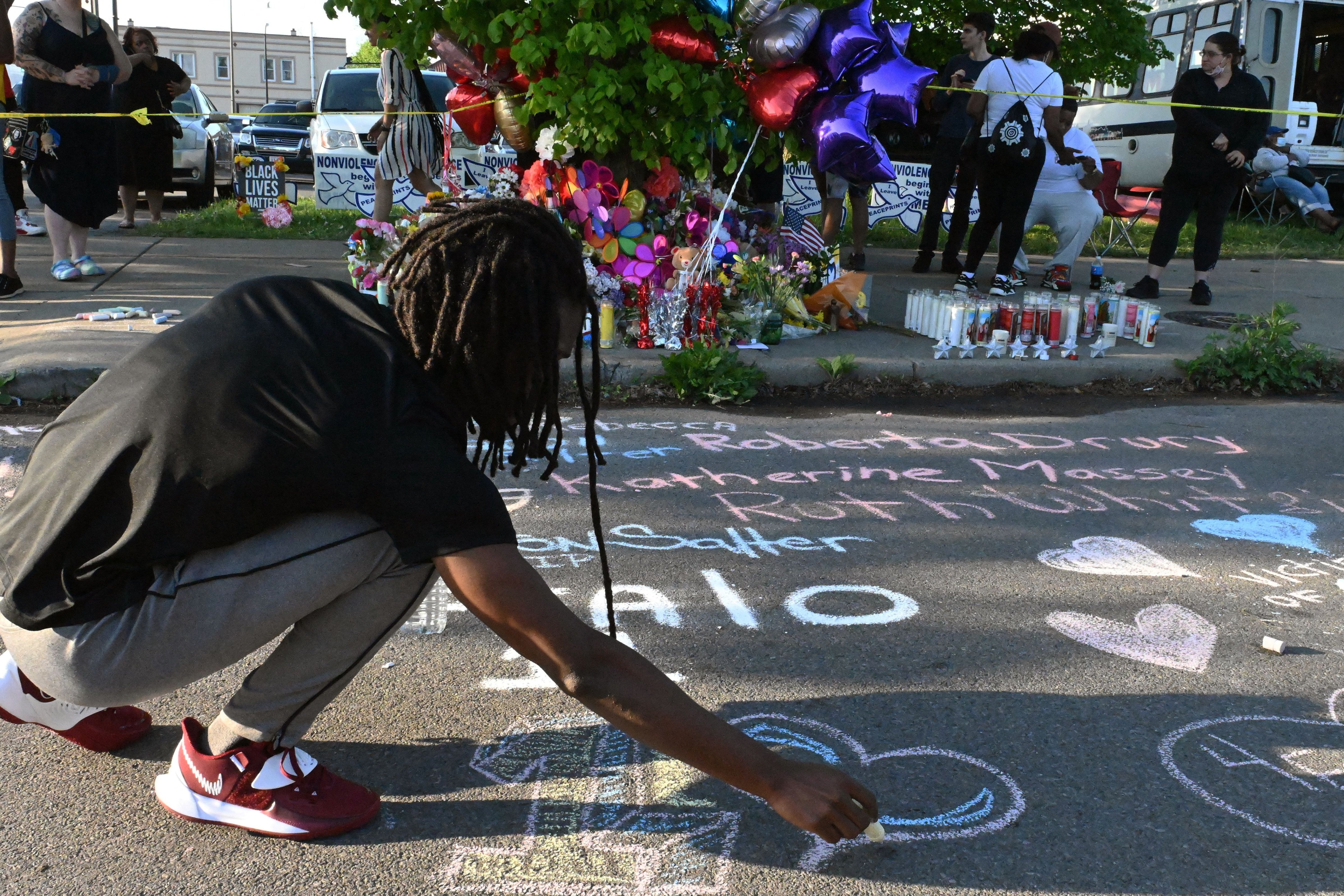 People leave messages at a makeshift memorial near a Tops grocery store in Buffalo, N.Y., on May 15, 2022, the day after a gunman shot and killed 10 people. (Usman Khan—AFP/Getty Images)