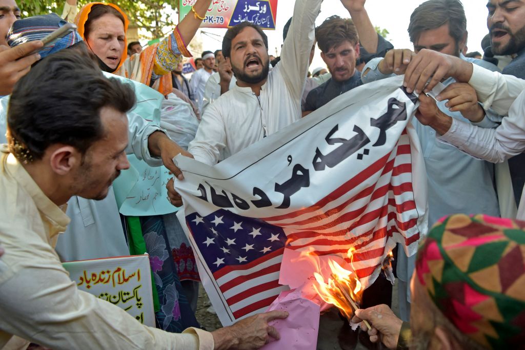 Supporters of ruling Pakistan Tehreek-e-Insaf (PTI) party burn a U.S.  flag during an anti-U.S. protest in Peshawar on April 1, 2022. (ABDUL MAJEED/AFP via Getty Images)