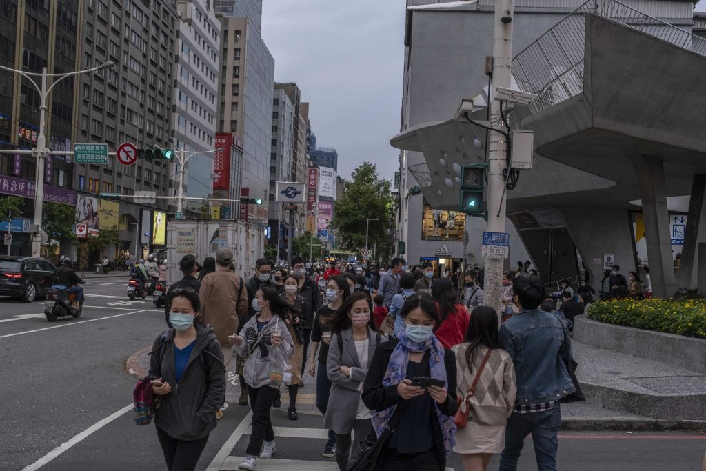 Pedestrians wearing protective masks cross a street at a shopping district in Taipei, Taiwan, on Saturday, April 16, 2022. (Lam Yik Fei/Bloomberg via Getty Images)