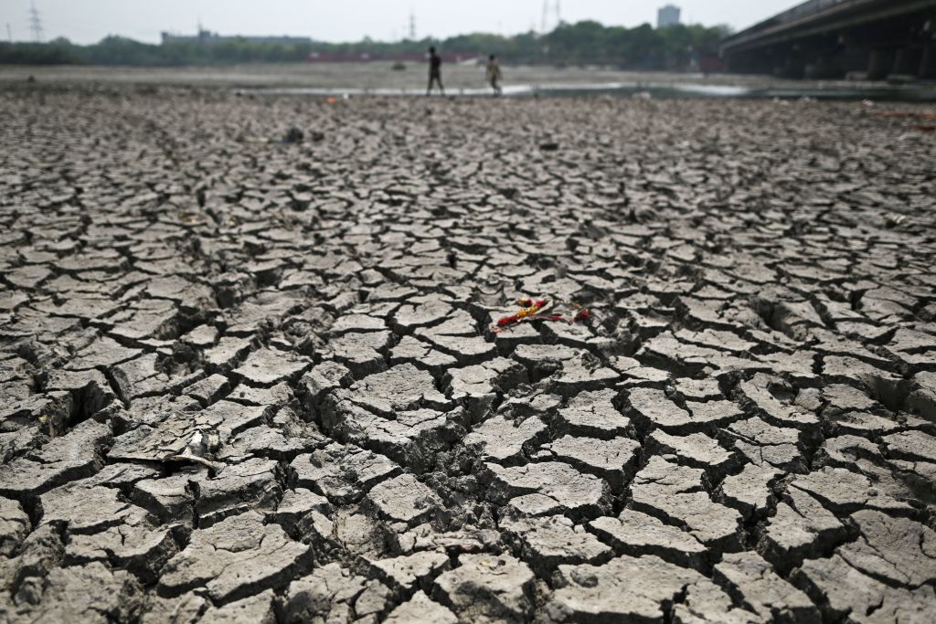 People walk across a parched riverbed on a hot summer day in New Delhi, May 2, 2022. (Sajjad Hussain—AFP/Getty Images)