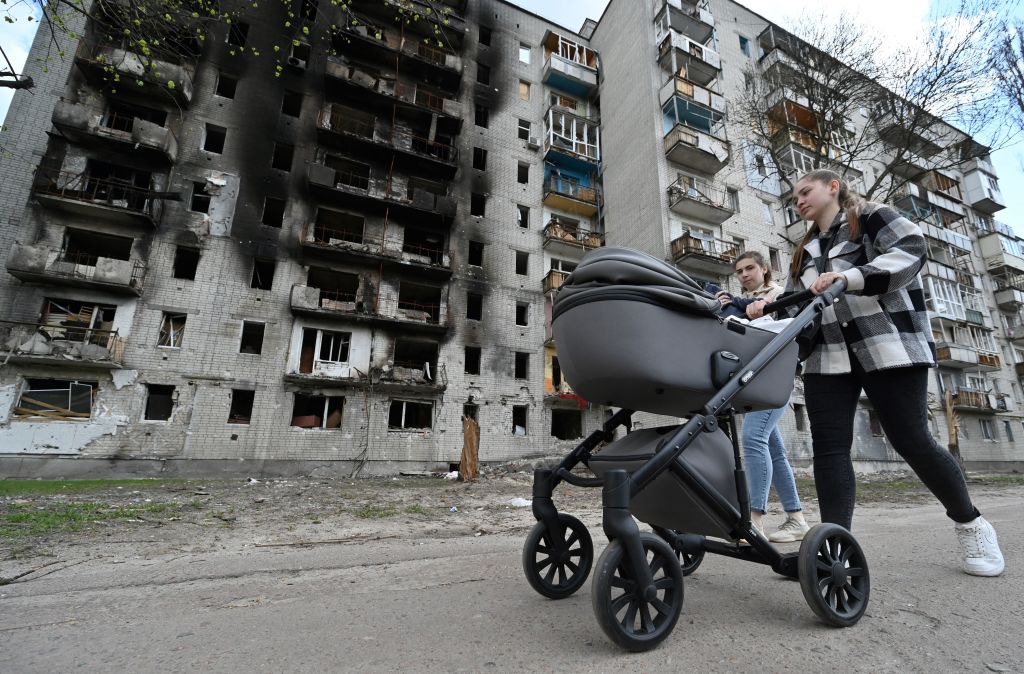 A woman pushes a pram past a heavily damaged residential building in the northern Ukrainian city of Chernigiv on May 3, 2022, amid the Russian invasion of Ukraine. (Genya Savilov—AFP/Getty Images)