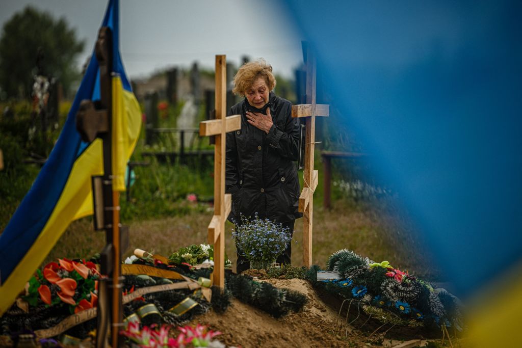 A woman mourns while visiting the grave of Stanislav Hvostov, 22, a Ukrainian serviceman killed during the Russian invasion of Ukraine, in the military section of the Kharkiv cemetery number 18 in Bezlioudivka, eastern Ukraine on May 21, 2022. (Dimitar DILKOFF-AFP)