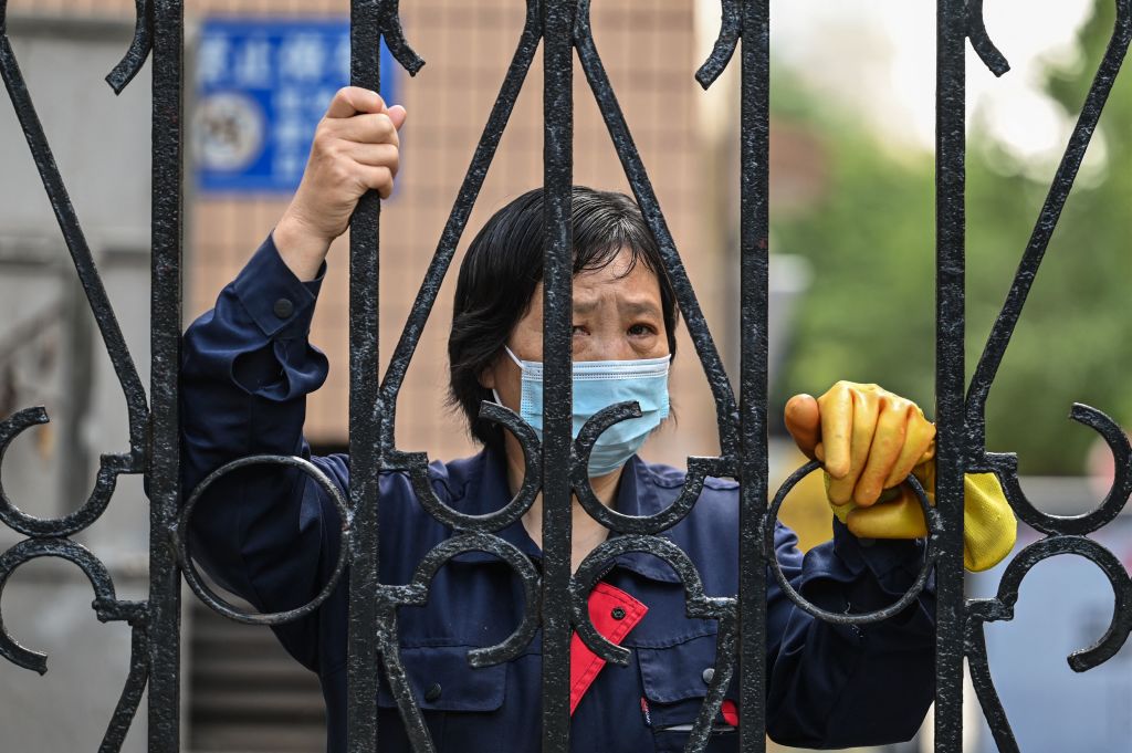 A worker looks past a fence in a compound during a Covid-19 coronavirus lockdown in the Jing'an district of Shanghai on May 25, 2022. (HECTOR RETAMAL/AFP via Getty Images)