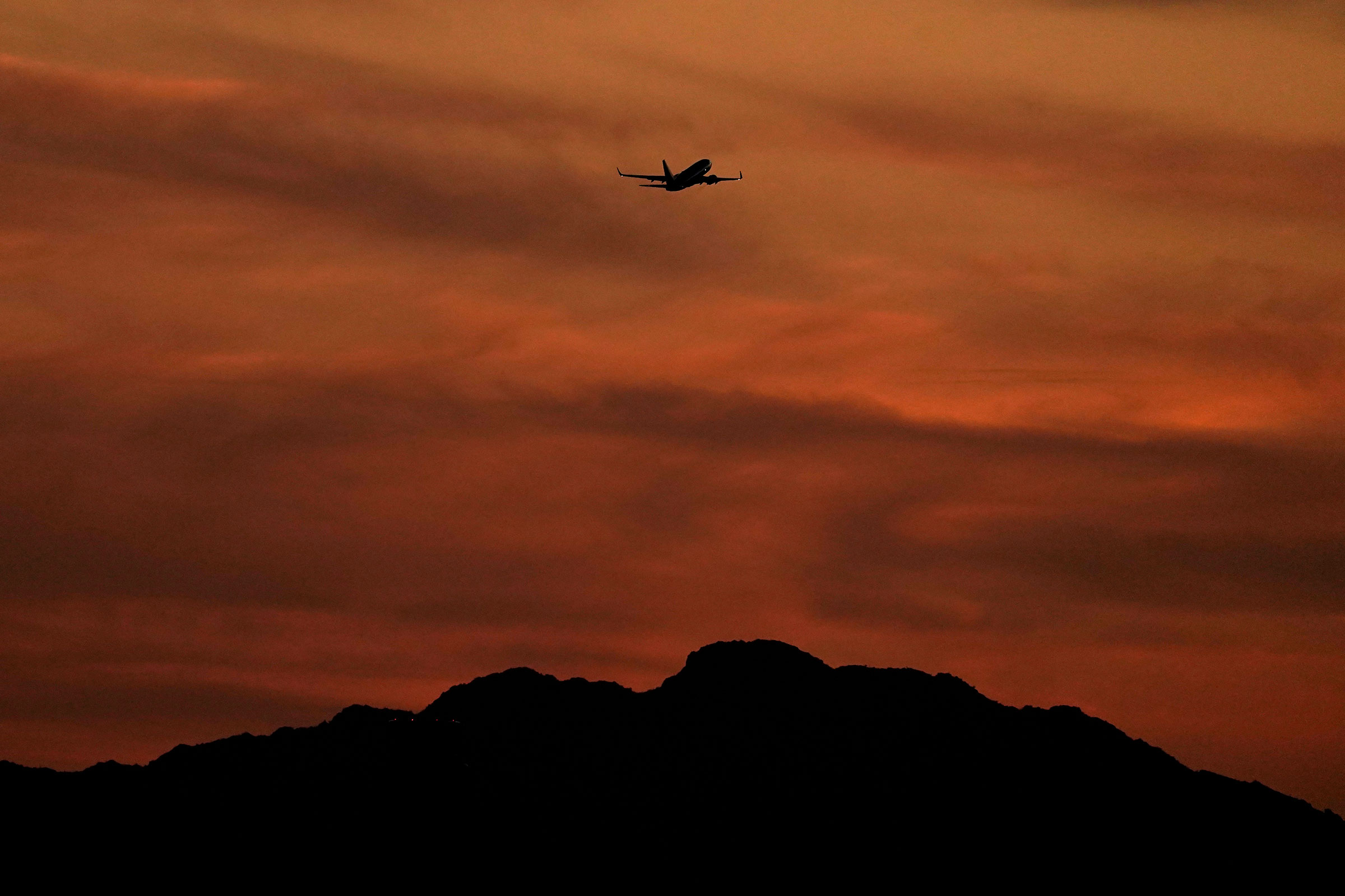 A passenger jet is silhouetted against the sky at dusk as it takes off from Sky Harbor Airport in Phoenix, on April 2, 2022. (Charlie Riedel—AP)