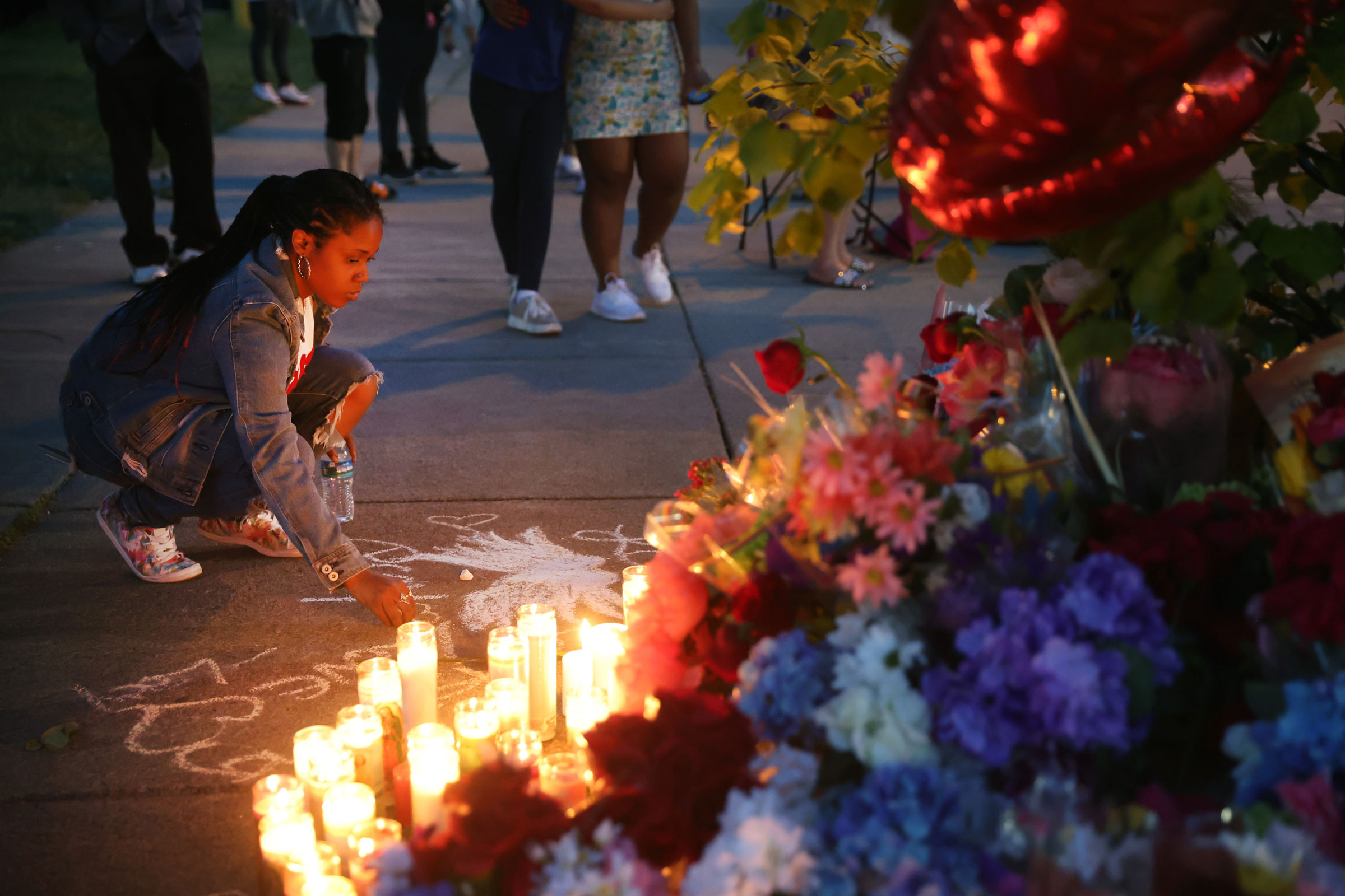 A woman chalks a message at a makeshift memorial outside of Tops market on May 15, 2022 in Buffalo, New York. (Scott Olson—Getty Images)