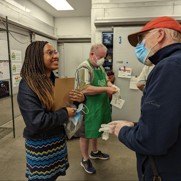 Chabeli Wells (left), volunteer coordinator at the Arlington Food Assistance Center, greets  volunteers as they arrive.