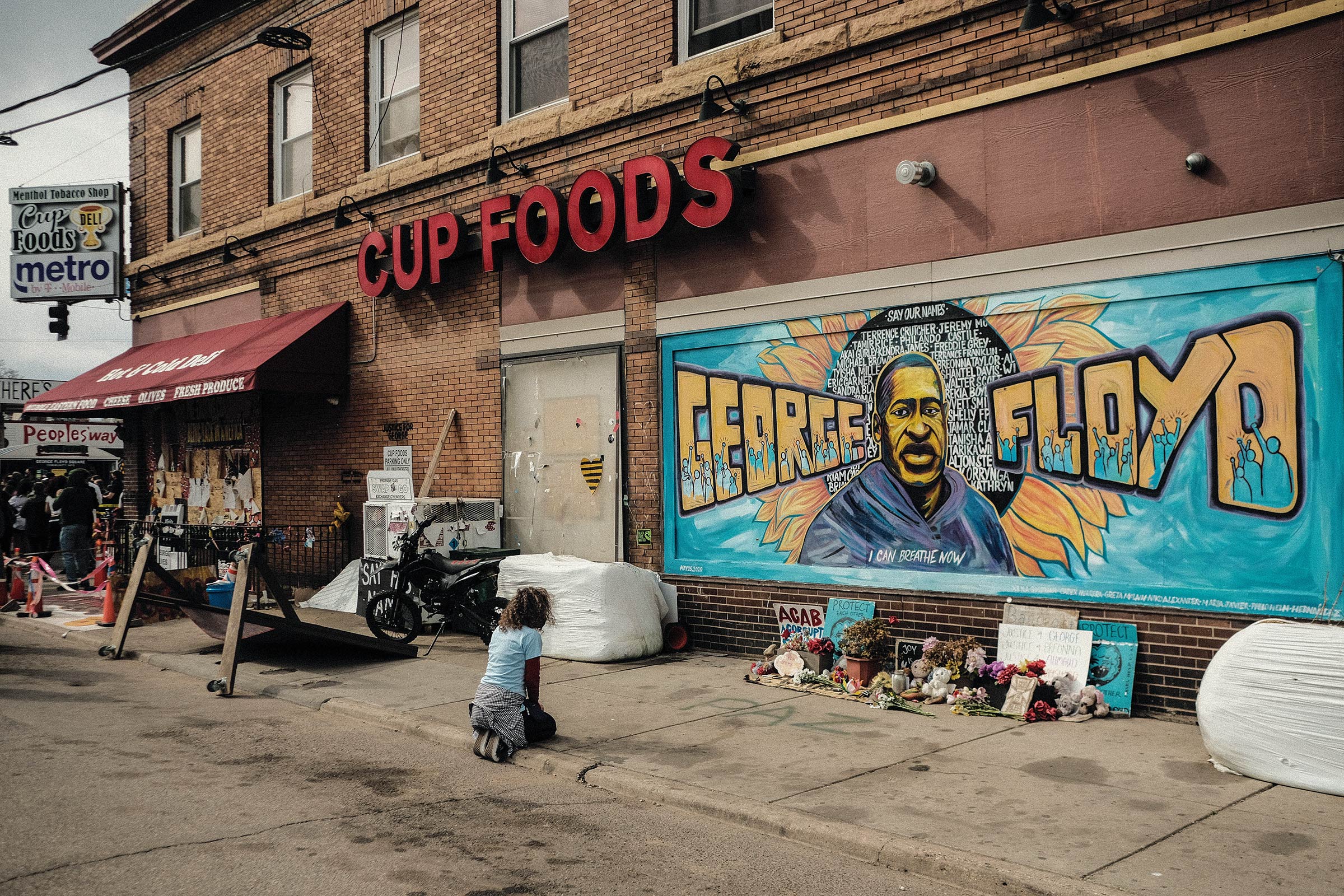 A woman pays respect to a mural of Floyd by the Cup Foods where he was murdered. (Matthew Hatcher—SOPA Images/LightRocket/Getty Images)