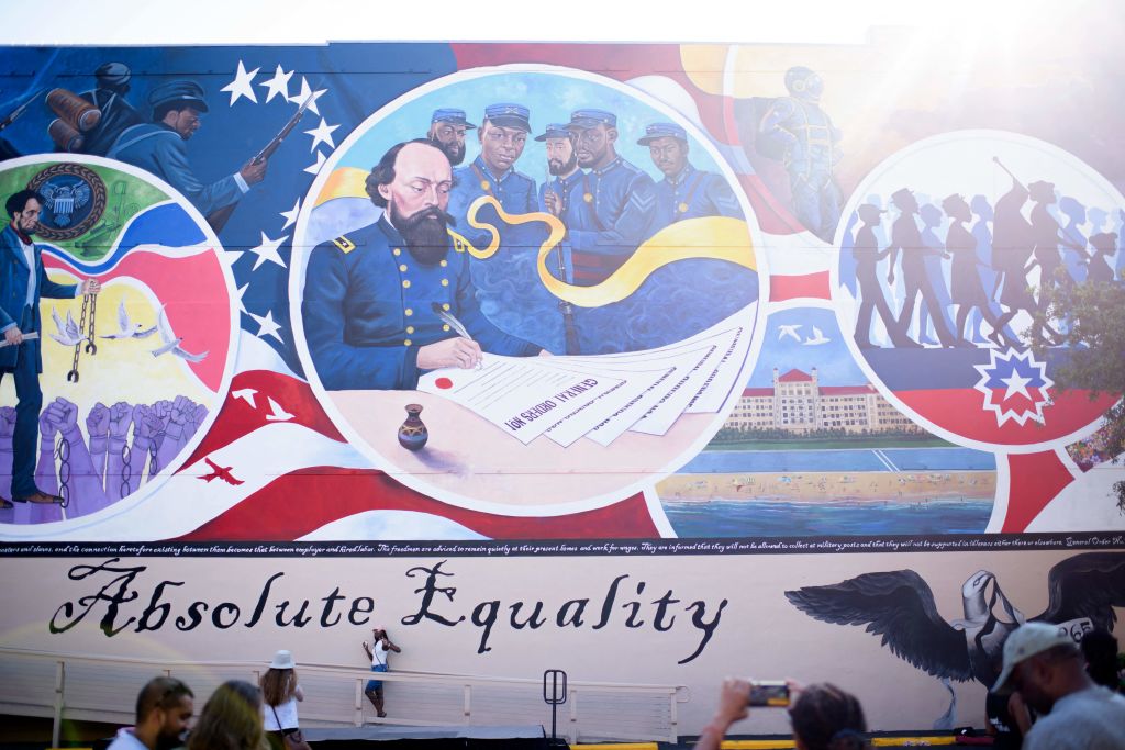 People take pictures next to a mural depicting the signing of General Order No. 3 during a Juneteenth celebration in Galveston, Texas, on June 19, 2021. (Mark Felix—AFP/Getty Images)