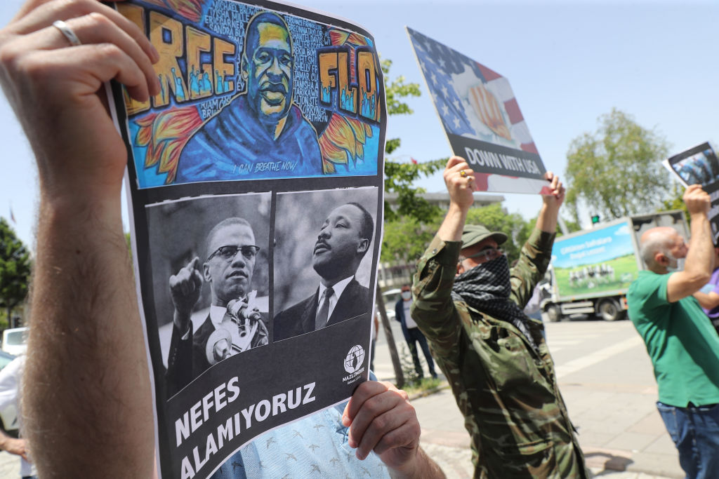 A protester holds a placard bearing the images of George Floyd, Malcom X and Martin Luther King on June 8, 2020, in Ankara, during a demonstration against racism and police brutality (ADEM ALTAN/AFP via Getty Images)