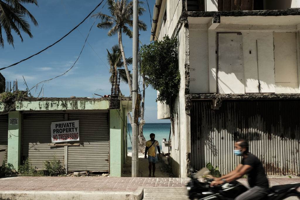 A motorcyclist drives past shuttered stores in Boracay, Aklan, the Philippines, on Wednesday, March 23, 2022. (Veejay Villafranca/Bloomberg via Getty Images)