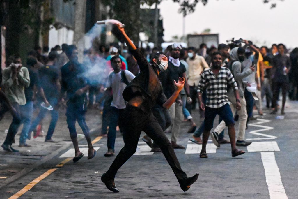 A demonstrator throws back a tear gas canister fired by police to disperse students taking part in an anti-government protest demanding the resignation of Sri Lanka's President Gotabaya Rajapaksa over the country's crippling economic crisis, in Colombo on May 29, 2022. (ISHARA S. KODIKARA-AFP)