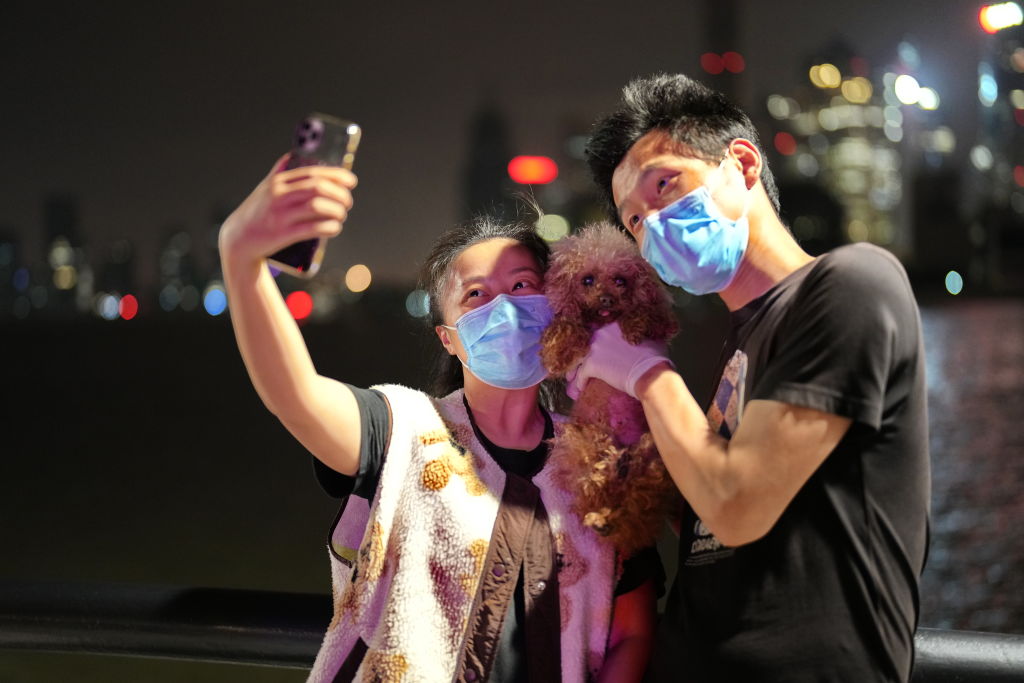 A couple and their pet dog take a selfie at the Bund at midnight on June 1, 2022 in Shanghai, China. (Zheng Xianzhang/VCG via Getty Images)