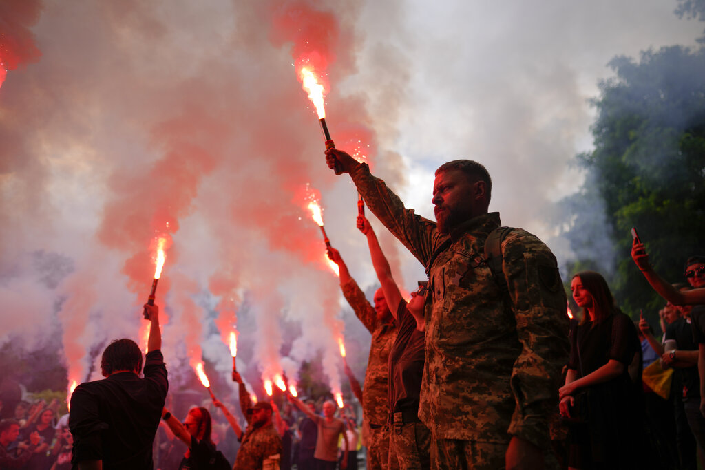 Soldiers hold flares as they attend the funeral of activist and soldier Roman Ratushnyi in Kyiv, Ukraine, on June 18, 2022. (Natacha Pisarenko—AP)