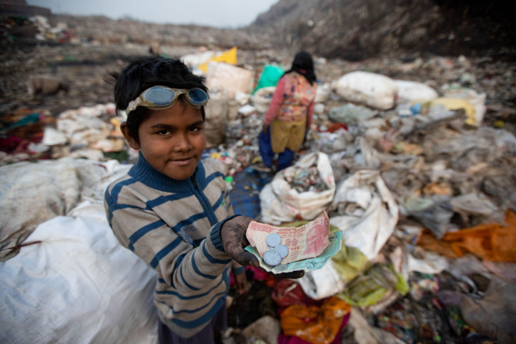A 10-year-old ragpicker shows the money he earned after selling recyclable items he collected at the Bhalswa garbage dump in New Delhi. (Vijay Pandey/Picture Alliance via Getty Images)