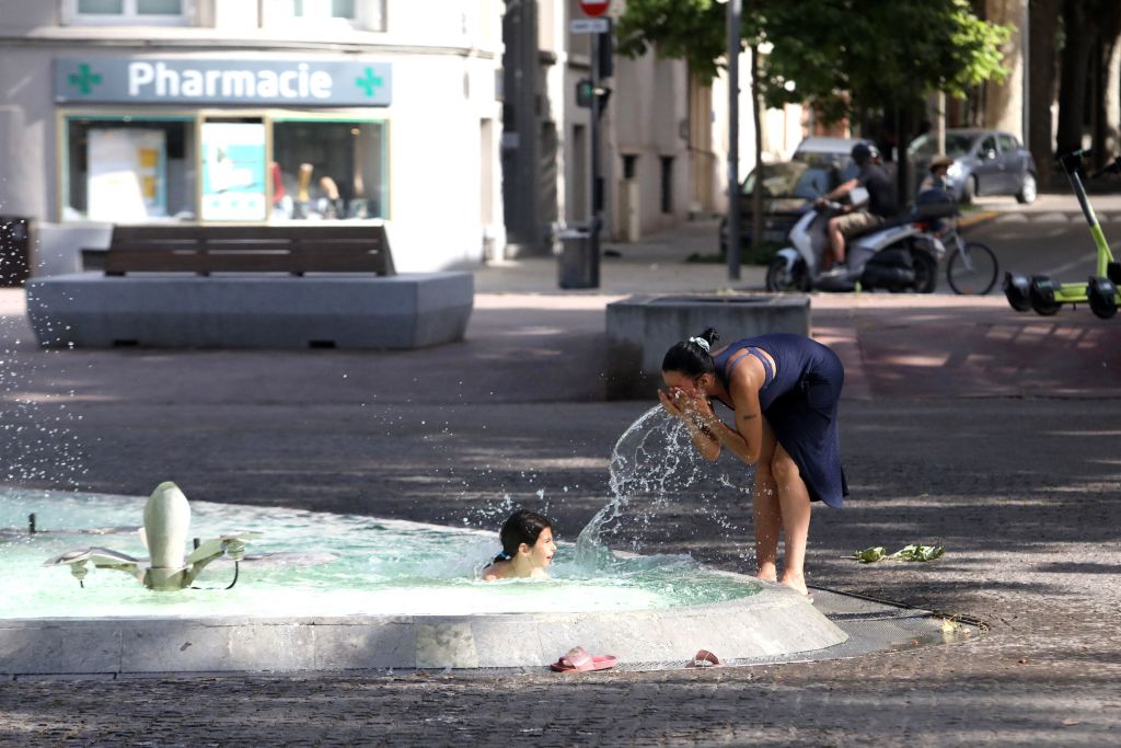 People cool off at a water fountain in Perpignan, a city in southern France on June 17, 2022, amid sweltering temperatures.