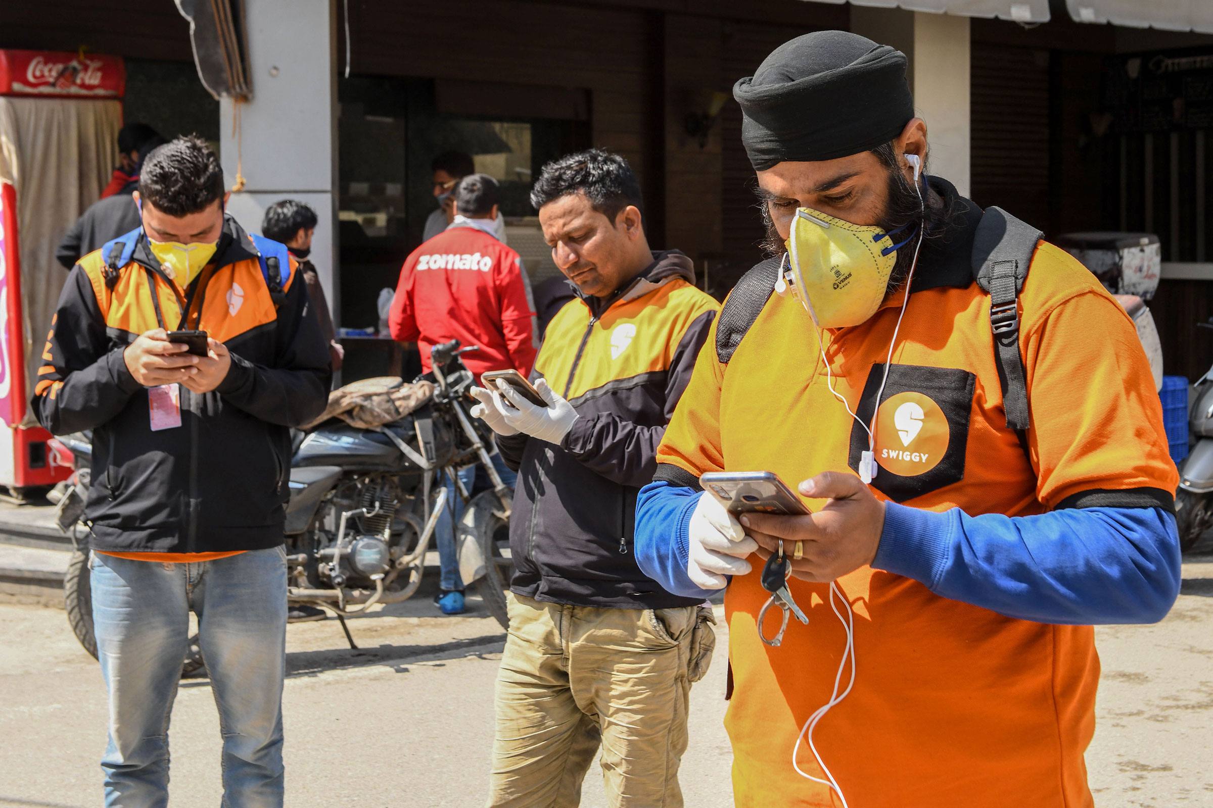 Swiggy delivery workers on mobile phones in Amritsar, India on March 28, 2020. (Narinder Nanu—AFP/Getty Images)