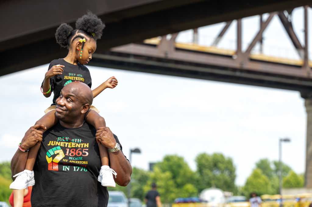 A young girl sits on a man's shoulders during the Louisville Juneteenth Festival at the Big Four Lawn on June 19, 2021, in Louisville, Kentucky. (Jon Cherry—Getty Images)
