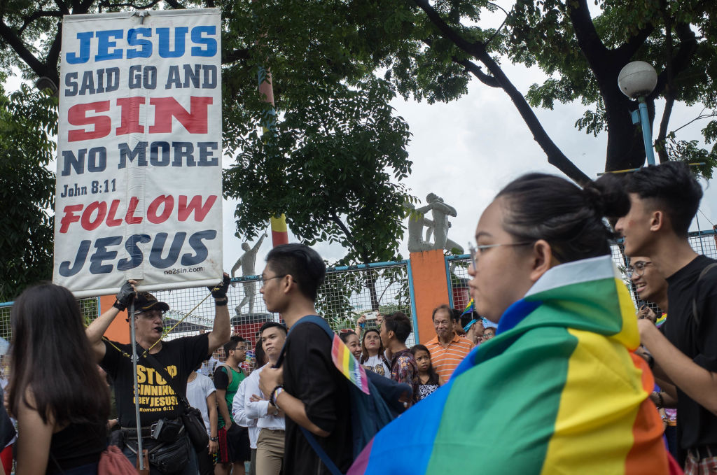 Members of the lesbian, gay, bisexual, and transgender (LGBT) community walk past a religious heckler during the annual LGBT pride celebration in Marikina City, east of Manila, Philippines, on 30 June 2018. (Richard James Mendoza—NurPhoto/Getty Images)