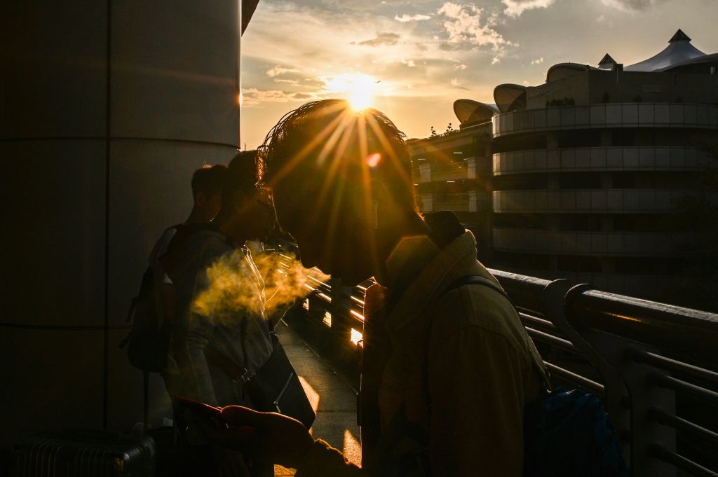 A man smokes a cigarette as the sun begins to set at Kuala Lumpur International Airport in Sepang on November 24, 2019. (MOHD RASFAN/AFP via Getty Images)
