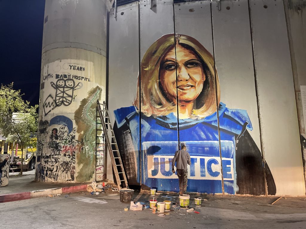 Palestinian artist Takiyuddin Sebatin preparing a graffiti on the separation wall in the West Bank for U.S. President Joe Biden, who is planning to visit Bethlehem in the middle of this month, depicting the photograph of Al Jazeera journalist Shireen Abu Akleh, who was killed by Israeli forces, on July 6, 2022 in Bethlehem, West Bank. (Hisham K. K. Abu Shaqra—Anadolu Agency/Getty Images)