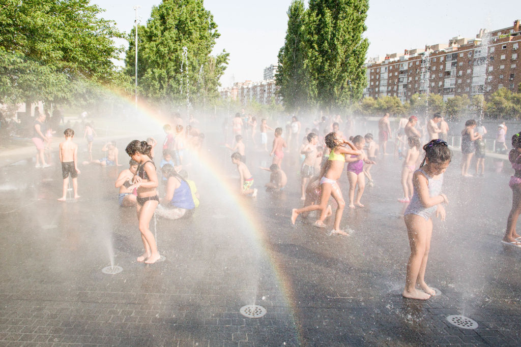 Children play and cool off in the water jets in Madrid on July 14. (Luis Soto—SOPA Images/LightRocket/Getty Images)